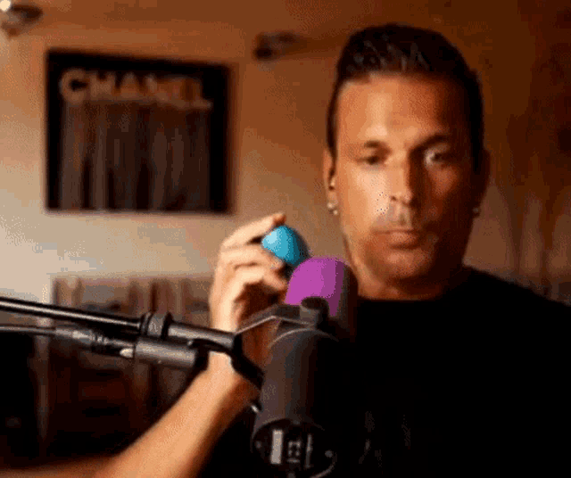 a man is holding a blue ball in front of a microphone in a room .