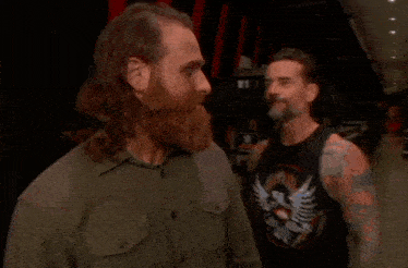 a man with a beard and long hair is standing in a hallway .
