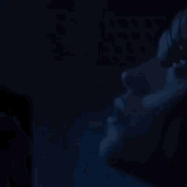 a close up of a person 's face in the dark with a blue light behind them .