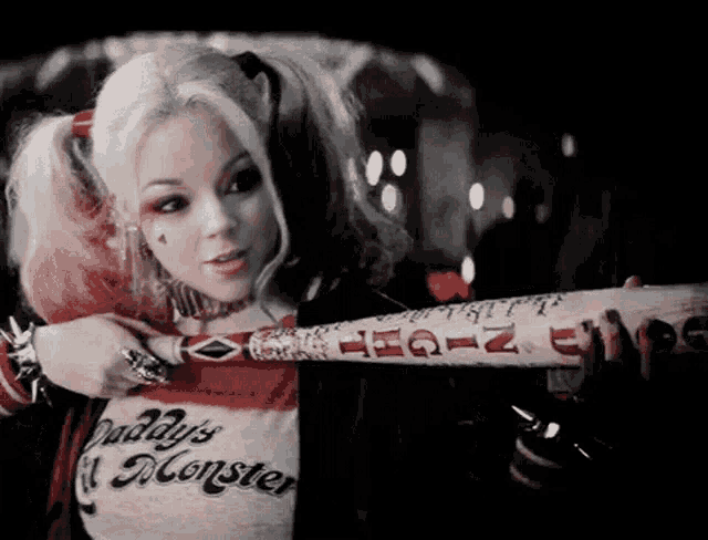 a woman in a harley quinn costume is holding a bat