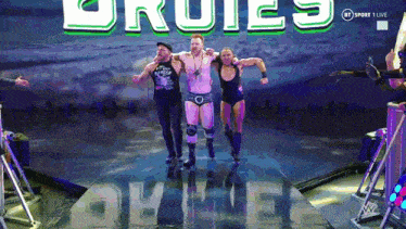 a group of wrestlers are walking on a stage in front of a sign that says rules