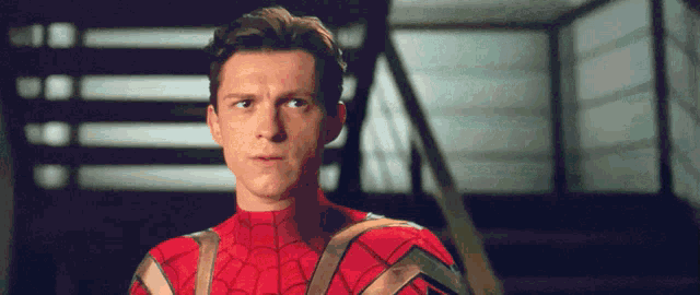 a man in a spiderman costume is standing in front of some stairs .
