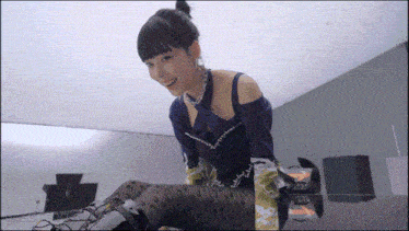 a woman in a blue top and black tights is sitting on the floor
