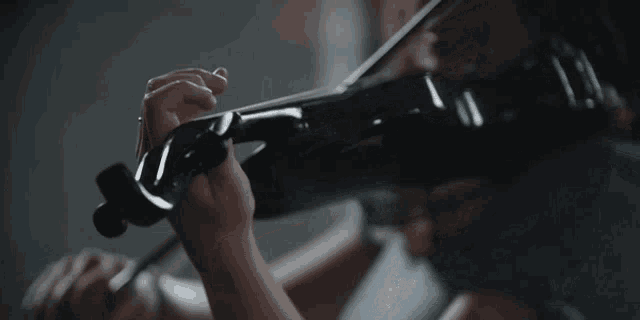 a woman is playing a violin in a dark room in front of a window .