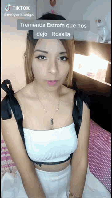 a woman in a white top and black ribbons on the sleeves is on a tiktok video