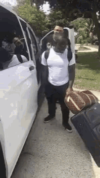 a man is getting out of a white van with a suitcase and a backpack .
