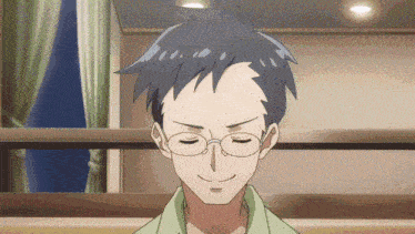 a man with glasses and a green shirt is smiling with his eyes closed