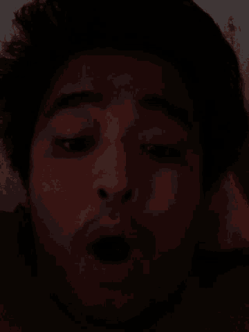 a man is sleeping in a dark room with his eyes closed .