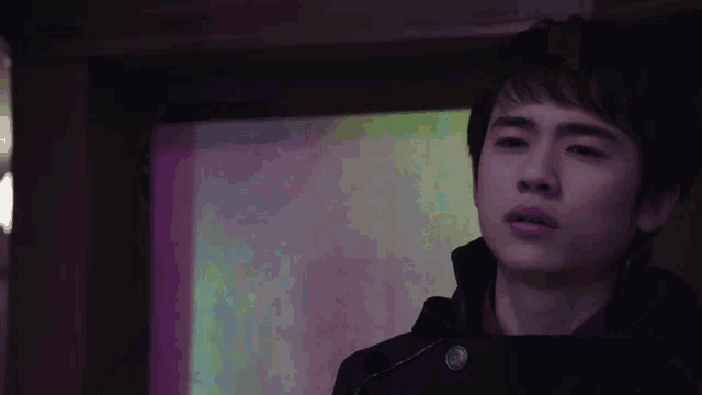 a close up of a young man 's face with a purple background behind him