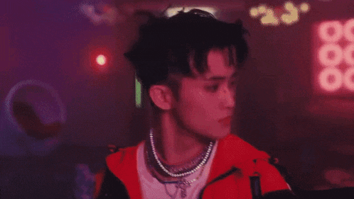 a close up of a person wearing a necklace and a red jacket .