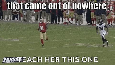 a football player in a red jersey is running on a field while another player in a white jersey is catching the ball .