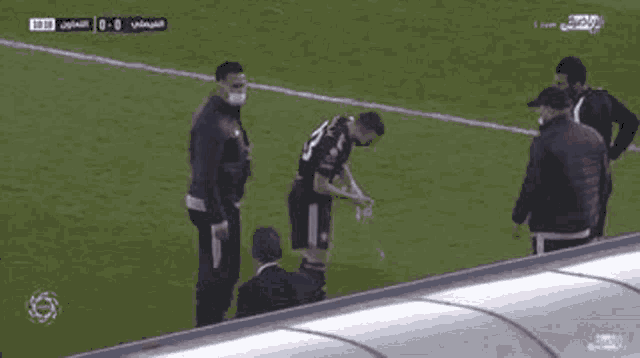 a soccer player is being helped off the field by a group of people wearing masks .