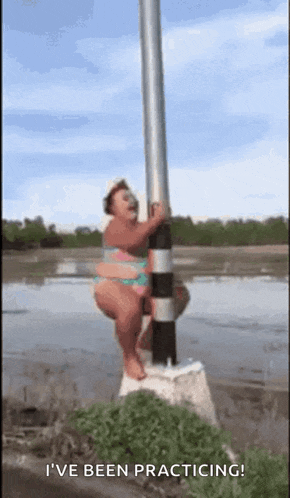 a woman in a bikini is standing on a pole in the water and says i 've been practicing .