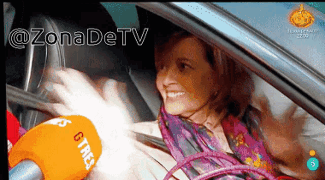 a woman in a car is being interviewed by a microphone that says gtres on it