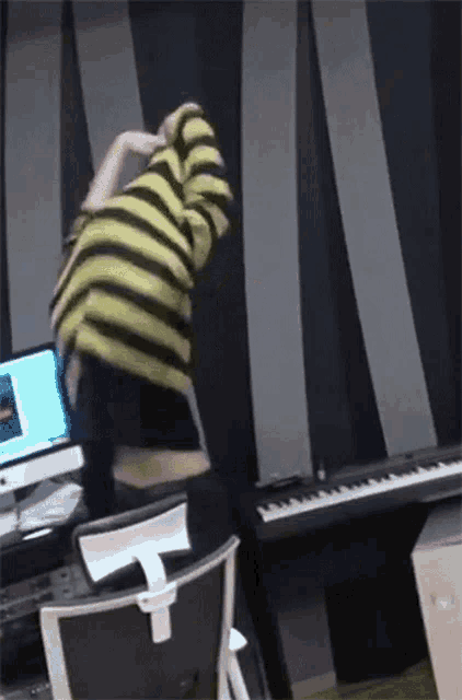 a person wearing a yellow and black striped shirt is standing in front of a keyboard