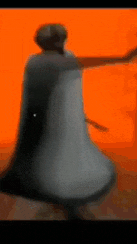 a blurry picture of a person holding a bell in front of an orange background .