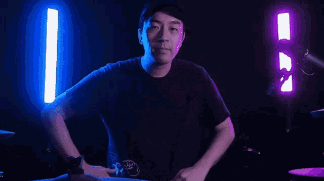a man is making a heart shape with his hands while standing in front of a microphone in a dark room .