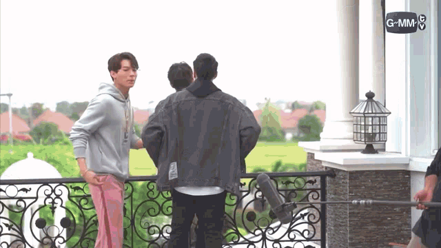 a group of men are standing on a balcony with a microphone in front of them .