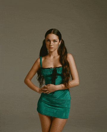 a woman in a green dress with pigtails is posing for a photo