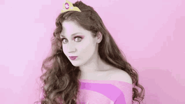a woman is wearing a tiara and a pink shirt .
