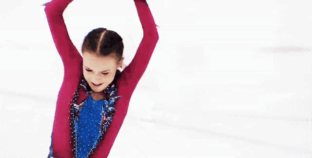 a female figure skater in a pink and blue outfit is smiling