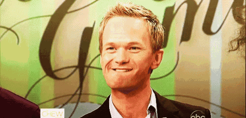 a man in a suit and tie smiles in front of a sign that says chew