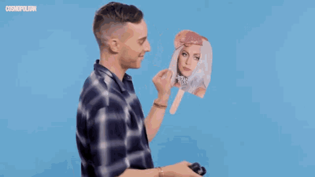 a man in a plaid shirt is holding an ice cream cone in front of his face with cosmopolitan written on the bottom