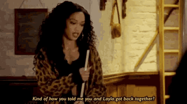a woman in a leopard print jacket is standing in a room talking to another woman .
