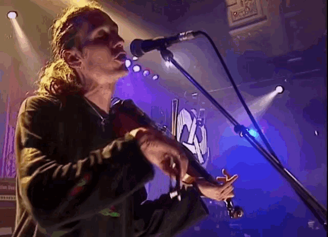 a man playing a violin and singing into a microphone