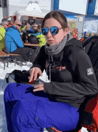 a woman wearing sunglasses and a jacket that says o'neill on it sits in the snow