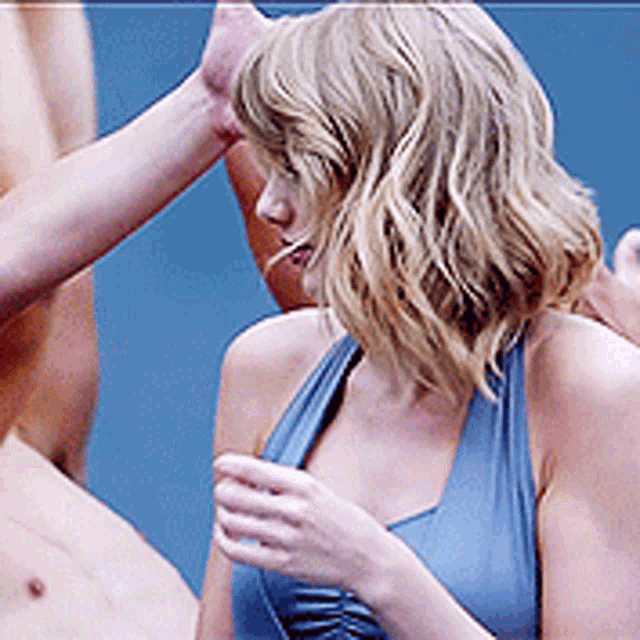 a woman in a blue tank top is being touched by a shirtless man