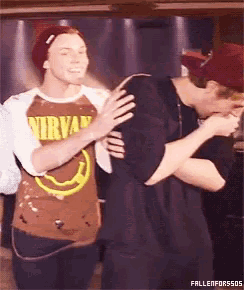a man wearing a brown nirvana shirt is hugging another man