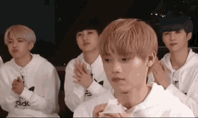 a group of young men wearing white adidas sweatshirts are clapping their hands together