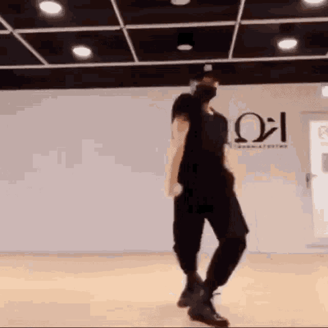 a man is dancing in a dance studio wearing a mask and a hat .
