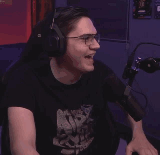a man wearing headphones and a t-shirt that says ' a ' on it is talking into a microphone
