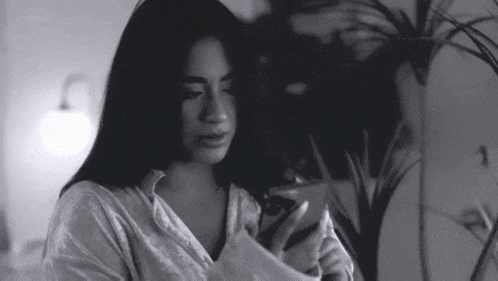a black and white photo of a woman using a cell phone