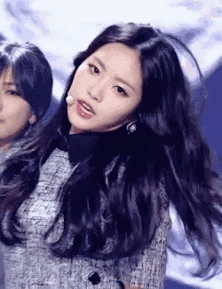 a woman with long black hair is wearing a grey jacket