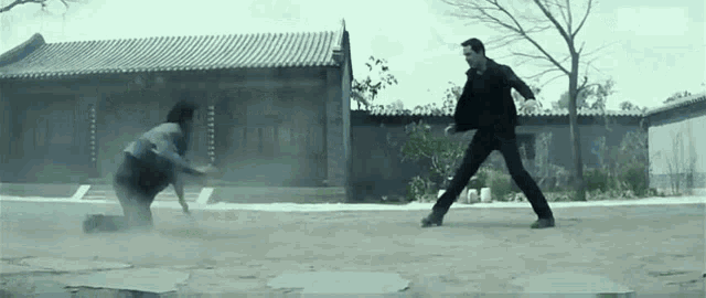 a man and a woman are fighting in a field in front of a building .