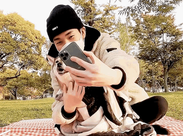 a man wearing an obey hat is taking a selfie with a dog