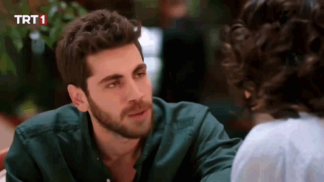 a man in a green shirt is talking to a woman in a white shirt with trt 1 written on the bottom