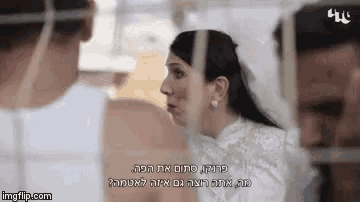 a woman in a wedding dress is talking to a man in a white shirt behind bars ..