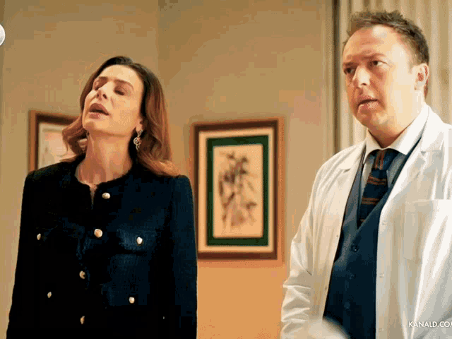 a man in a white coat stands next to a woman in a black jacket and gold buttons