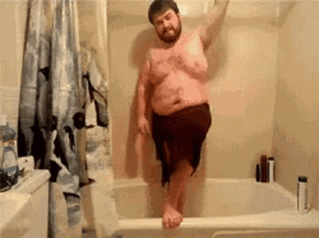 a shirtless man is standing in a bathtub with a shower curtain on the wall .