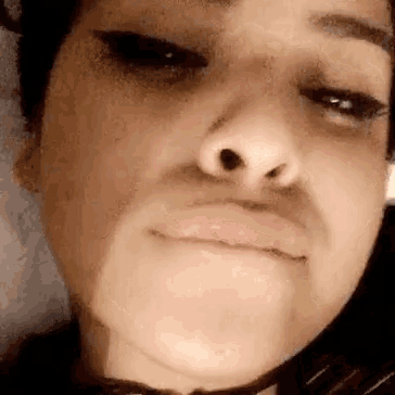 a close up of a woman 's face with a choker around her neck making a funny face .