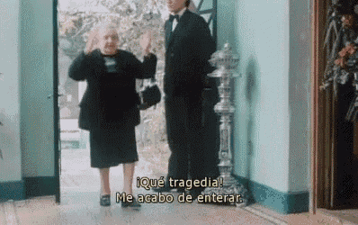 a man in a tuxedo and a woman in a black dress are standing in a hallway with subtitles in spanish
