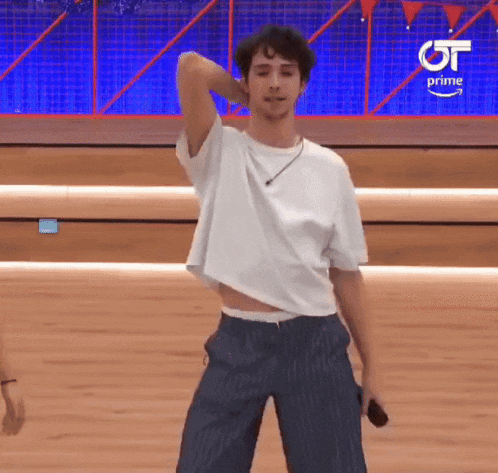 a man in a white shirt and blue striped pants is dancing on a stage with a microphone .