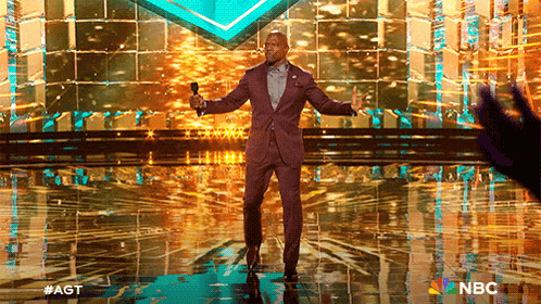 a man in a suit is standing on a stage with a microphone in his hand ..