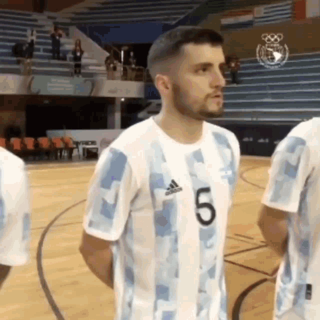 a man wearing a number 5 jersey is standing on a wooden court .