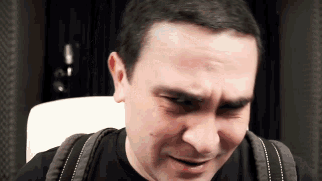 a man wearing a black shirt and a backpack is making a funny face
