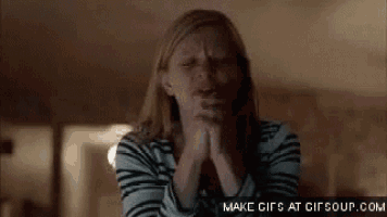 a woman in a striped shirt is crying with her hands folded in front of her face .